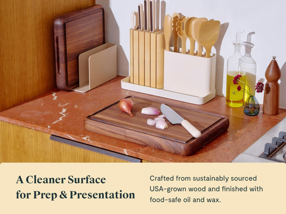 Caraway walnut butcher block with sliced garlic and a knife beside upright boards and utensils.