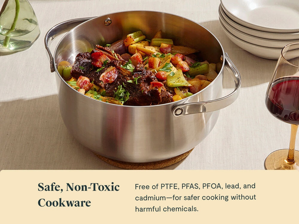 Caraway stainless steel Dutch oven serving a meat and vegetable dish on a dining table.