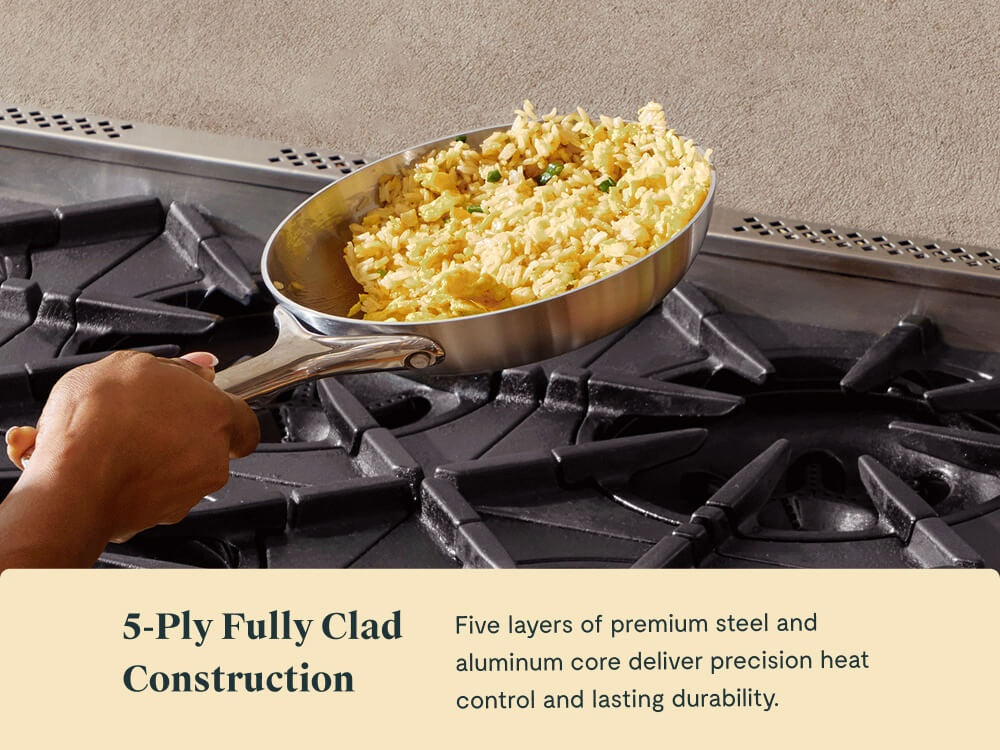 Hand tossing a cooked rice dish in a stainless steel mini fry pan on a stove.