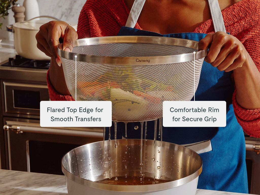 Person lifting a stainless steel strainer above a pot to drain water.