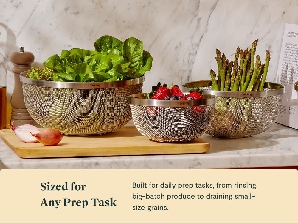 Three stainless steel strainers holding lettuce, berries, and asparagus.